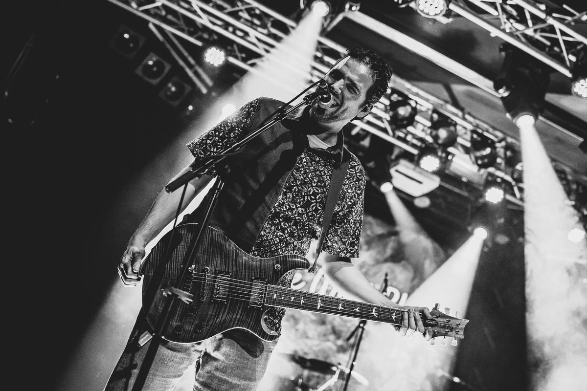 Singer and guitarist under spotlights, black and white